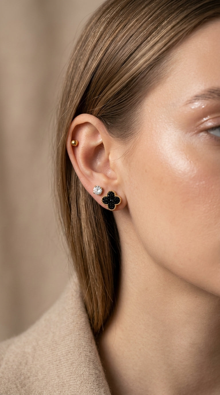 Close-up of a person wearing a black clover-shaped earring with a blurred background