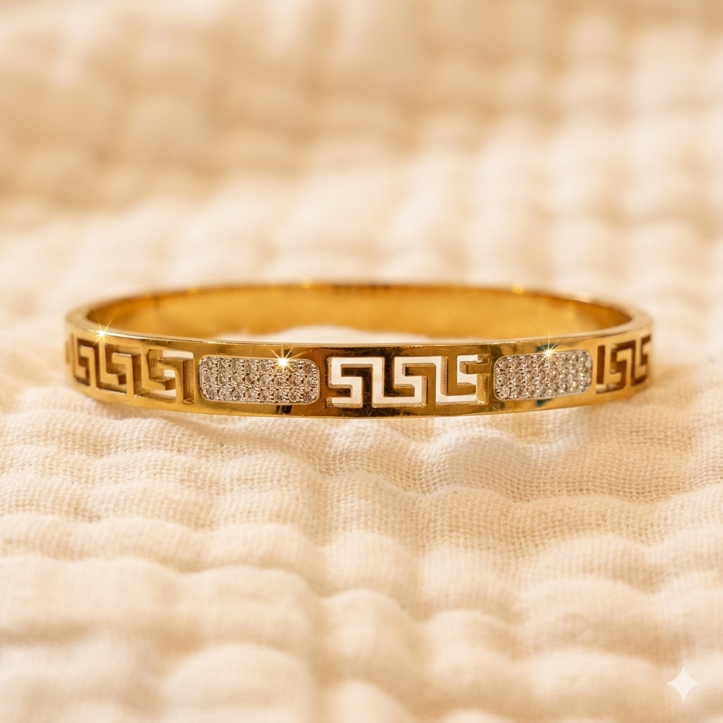Gold bracelet with intricate design on a textured beige background