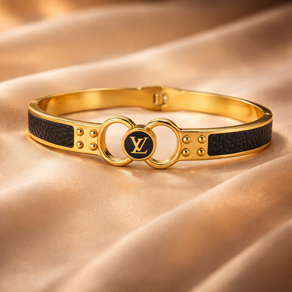 Gold bracelet with black leather straps on a satin background