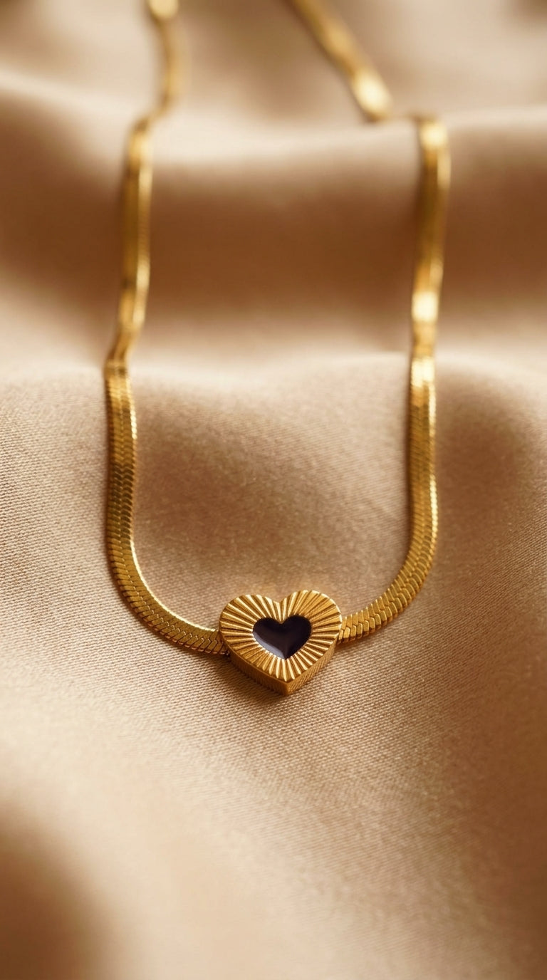 Gold necklace with a heart-shaped pendant on a beige fabric background
