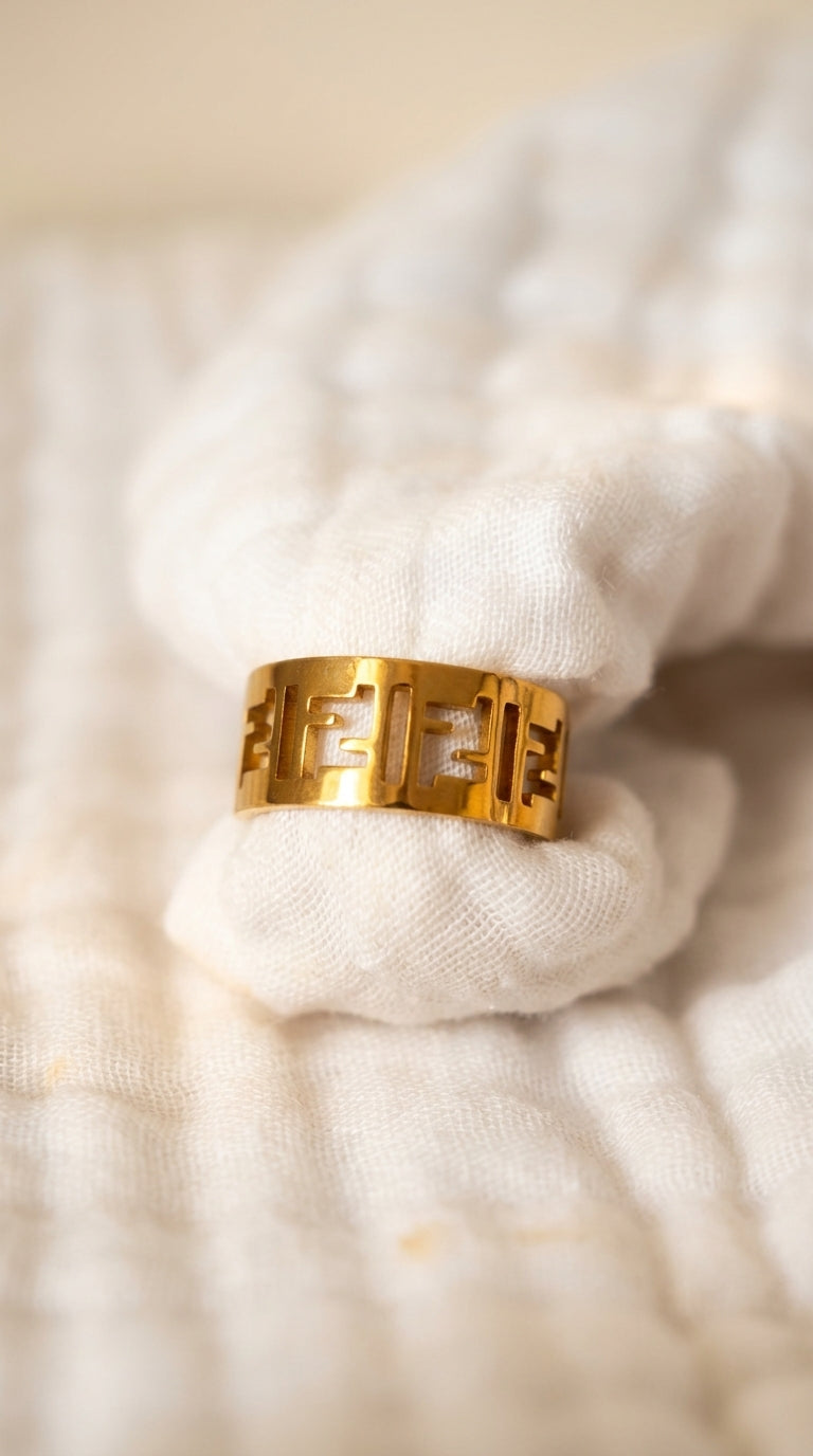 Gold ring with a brand logo on a textured white fabric background