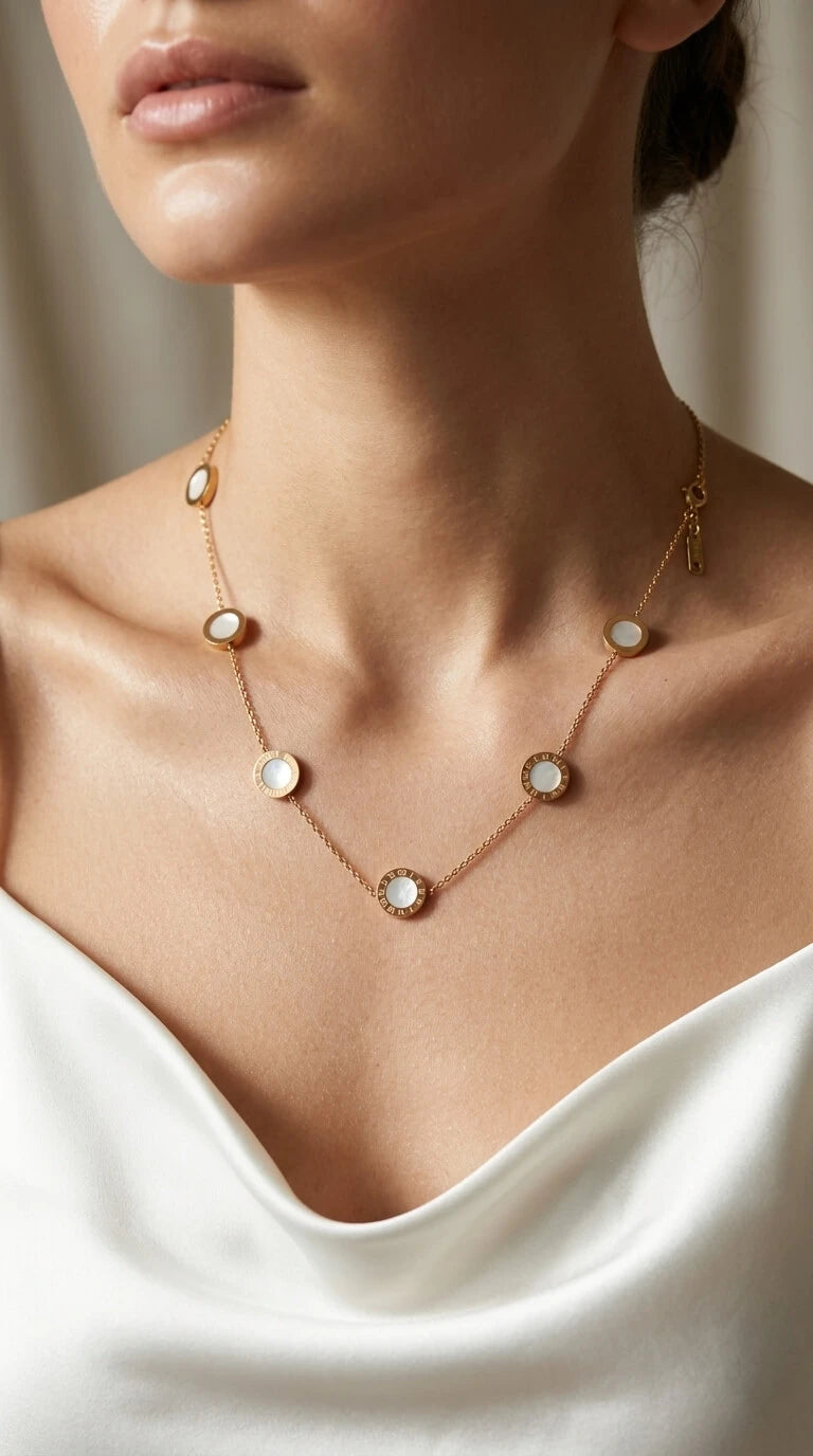Necklace with circular pendants on a person wearing a white top.