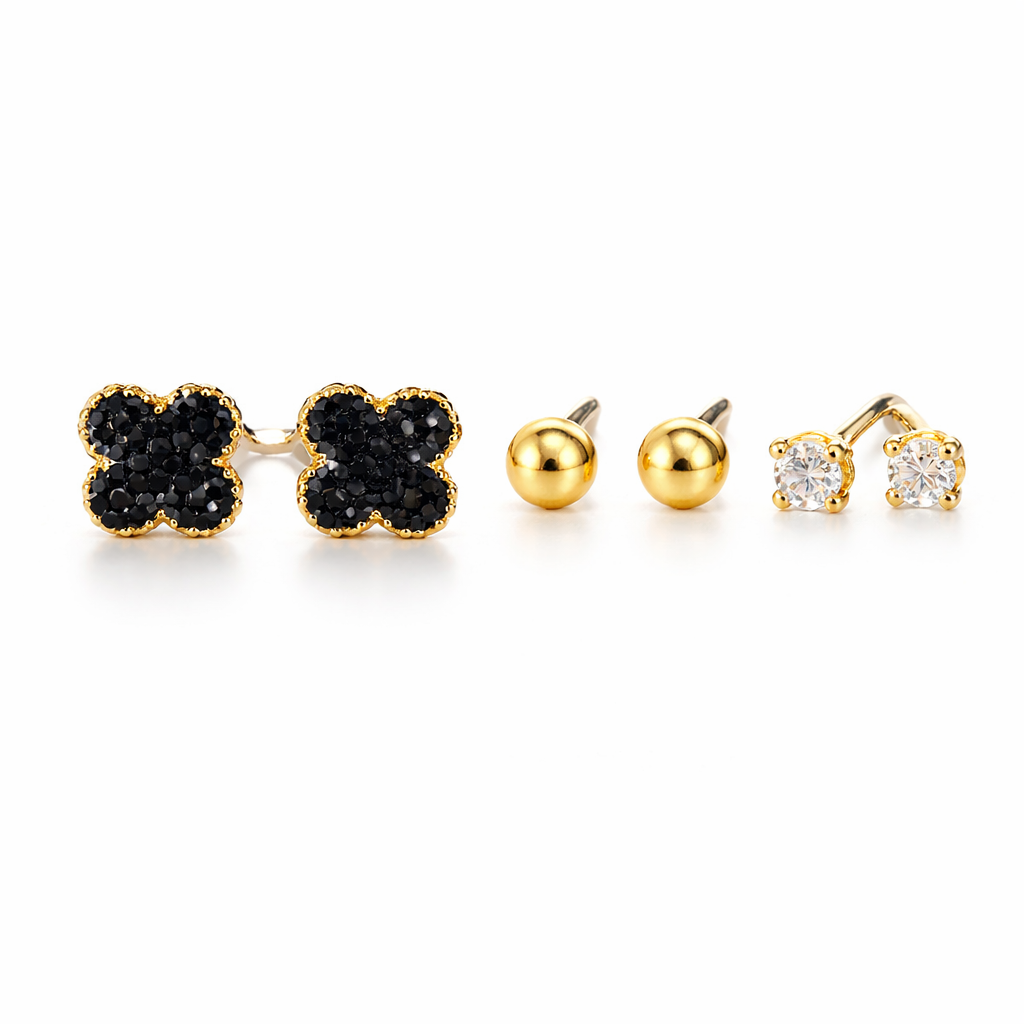 Set of gold and black clover-shaped earrings, gold ball earrings, and gold and diamond earrings on a white background.